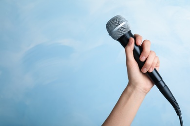 Woman holding modern microphone on color background, closeup. Space for text