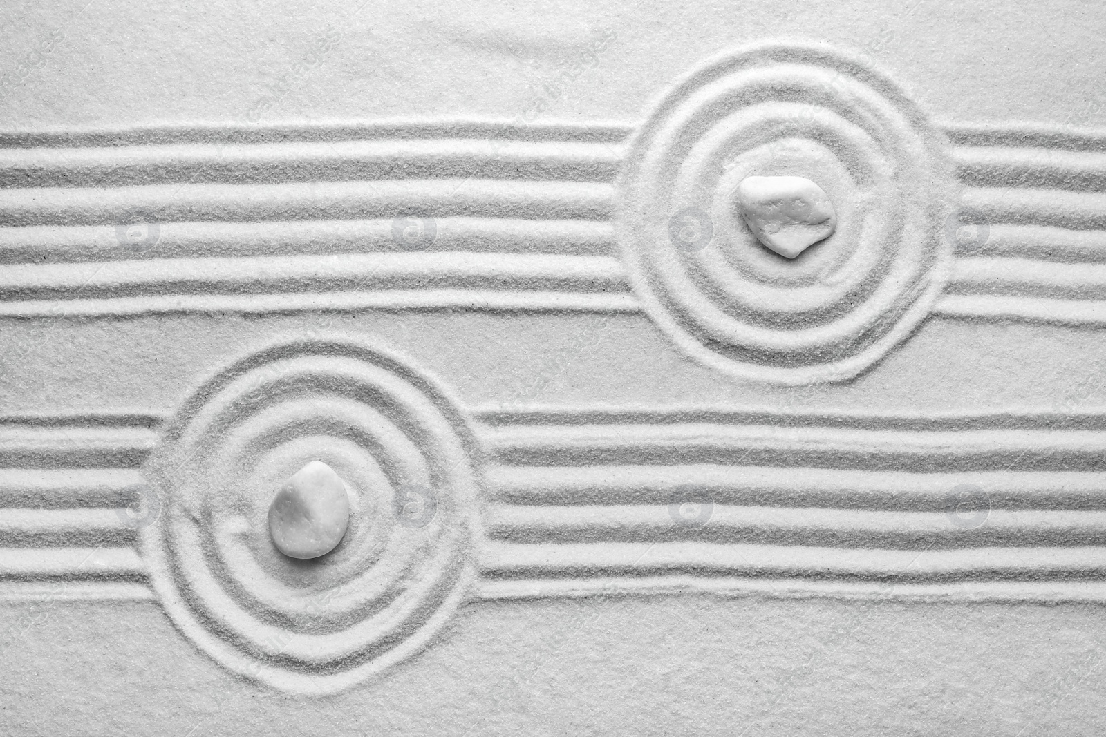 Photo of White stones on sand with pattern, top view. Zen, meditation, harmony