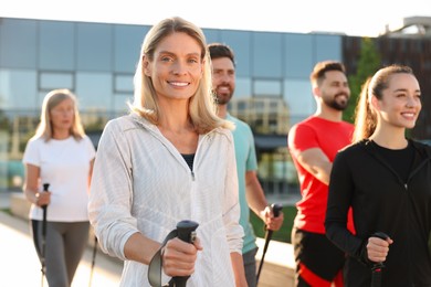 Photo of Group of people practicing Nordic walking with poles outdoors on sunny day