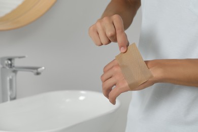 Photo of Man putting sticking plaster onto hand indoors, closeup. Space for text