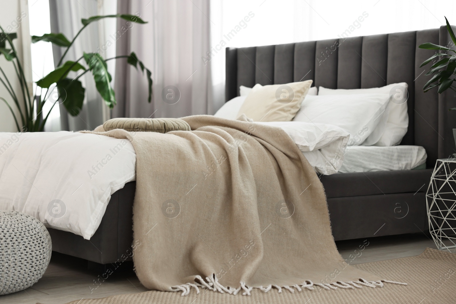 Photo of Soft beige plaid on bed in stylish bedroom. Interior design