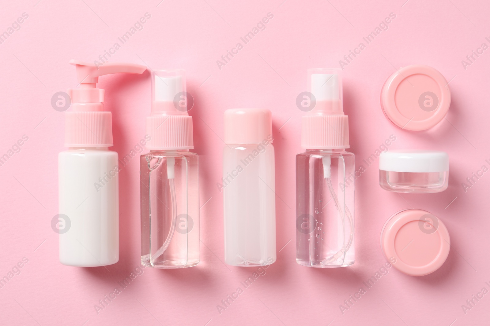 Photo of Cosmetic travel kit on pink background, flat lay. Bath accessories