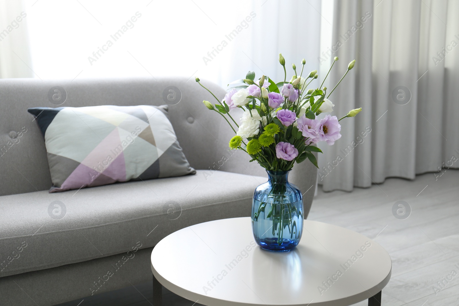 Photo of Bouquet of beautiful Eustoma flowers on table in room. Space for text