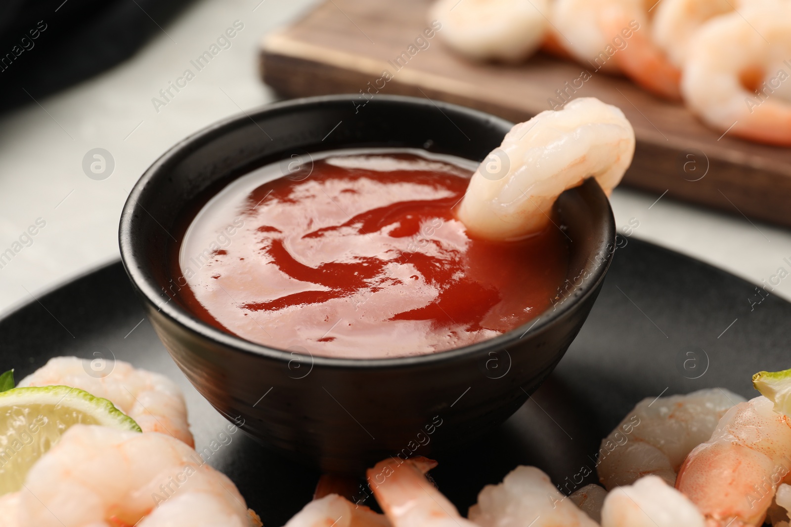 Photo of Tasty boiled shrimps with cocktail sauce and lime on table, closeup