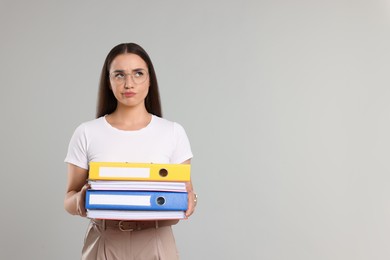 Photo of Unhappy woman with folders on light gray background, space for text