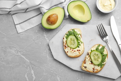 Slices of bread with spread and cucumber on grey marble table, flat lay