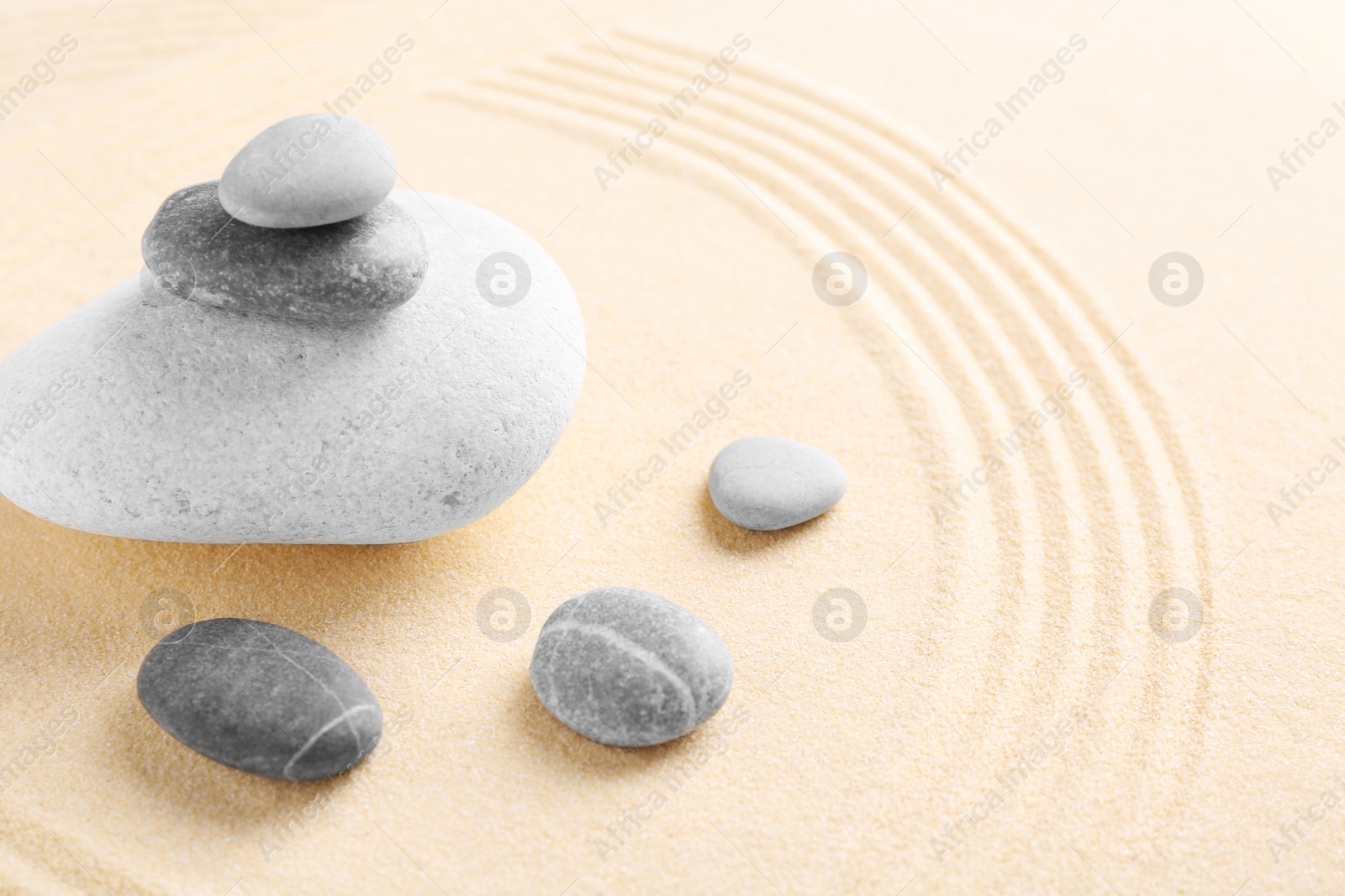 Photo of Zen garden stones on sand with pattern. Space for text