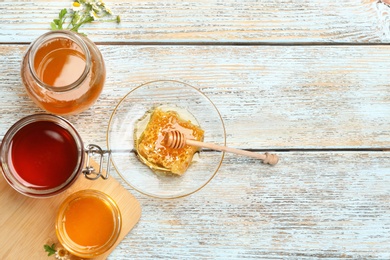 Flat lay composition with different types of honey on light blue wooden table. Space for text