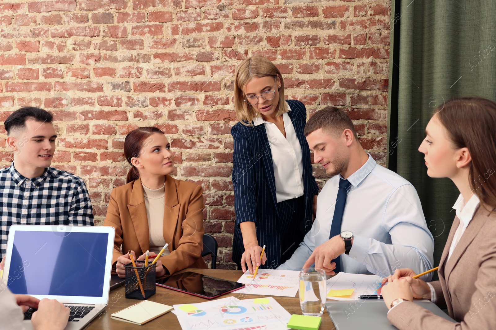 Photo of Businesswoman having meeting with her employees in office. Lady boss