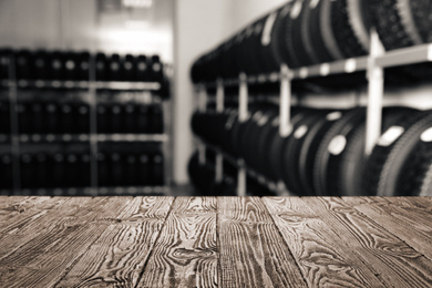 Image of Empty wooden surface and blurred view of car tires in auto store, closeup. Space for text 