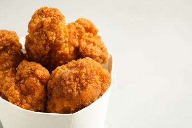 Tasty deep fried chicken pieces on light background, closeup. Space for text