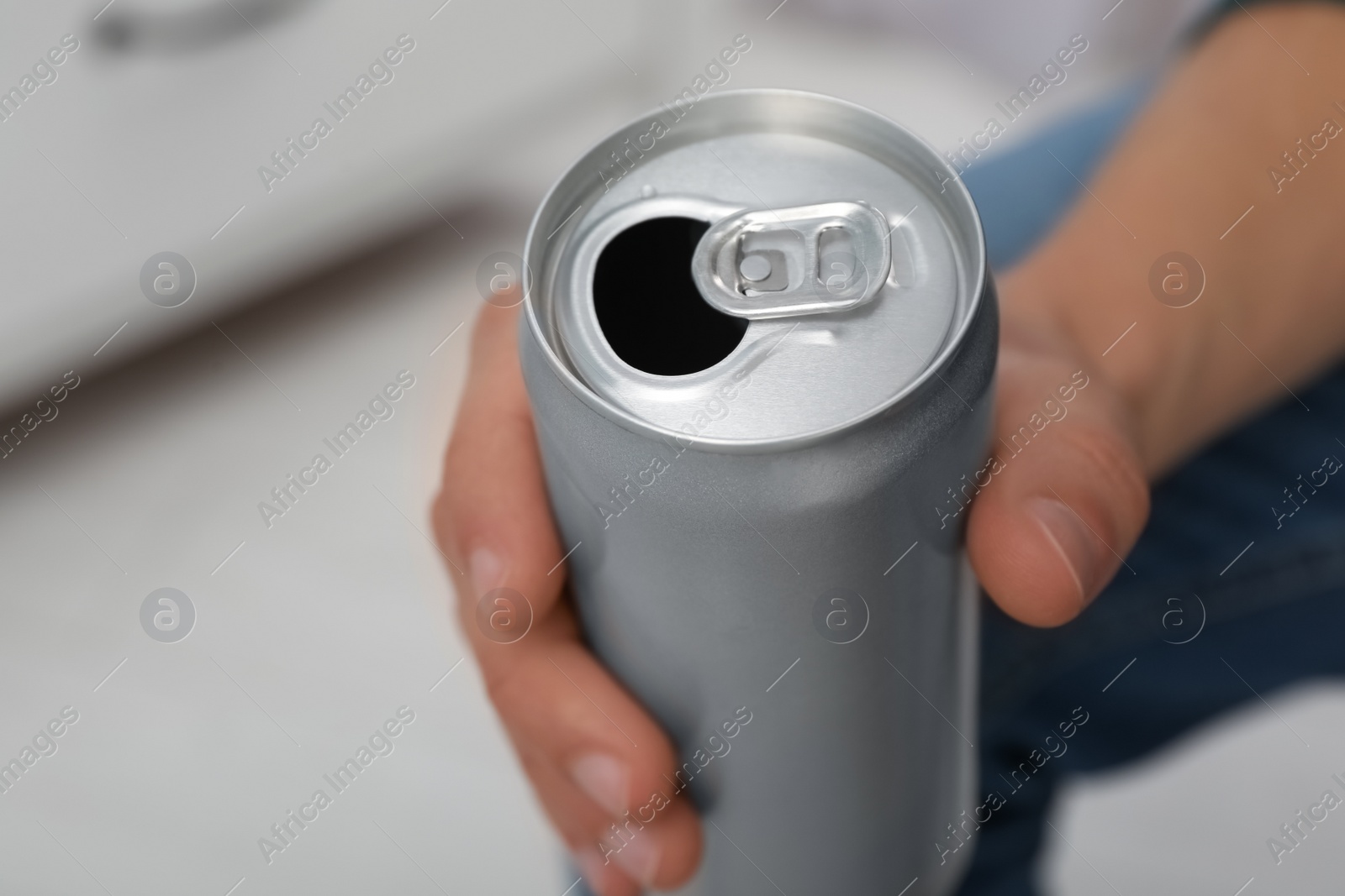 Photo of Man holding open aluminum can on blurred background, closeup. Space for design