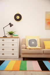 Photo of Modern room interior with comfortable sofa and rainbow carpet