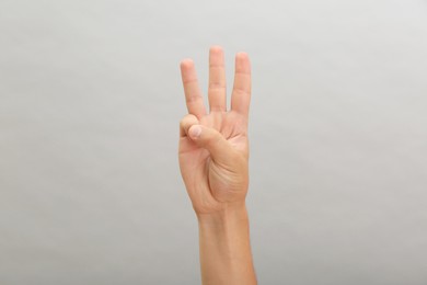 Photo of Teenage boy showing three fingers on light background, closeup