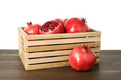 Photo of Fresh pomegranates in crate on wooden table against white background