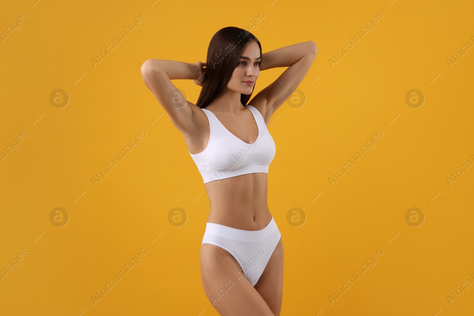 Photo of Young woman in stylish white bikini on orange background