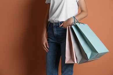 Photo of Woman with paper shopping bags on light brown background, closeup