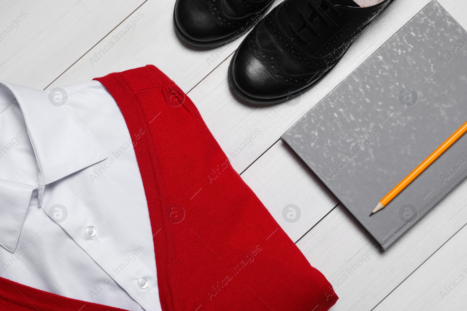 Photo of Stylish school for girl uniform and notebook on white wooden background, flat lay