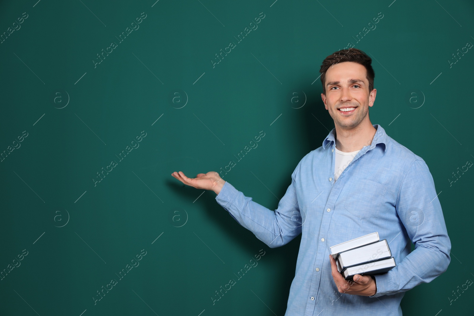 Photo of Portrait of male teacher with books on color background. Space for text