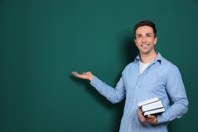 Portrait of male teacher with books on color background. Space for text