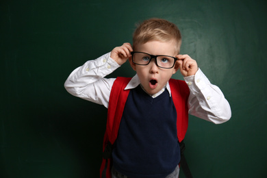 Funny little child wearing glasses near chalkboard. First time at school