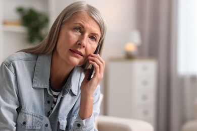 Senior woman talking on phone at home, space for text