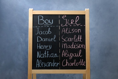 Photo of Chalkboard stand with baby names on blue background