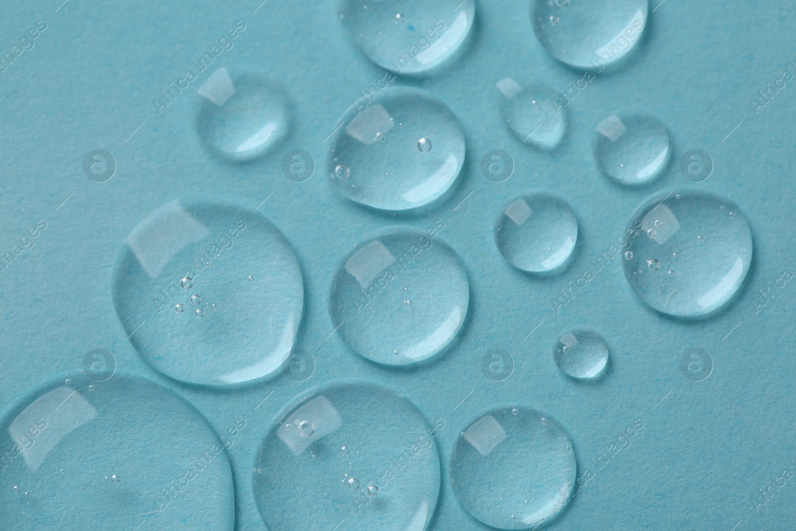 Photo of Drops of cosmetic serum on light blue background, top view