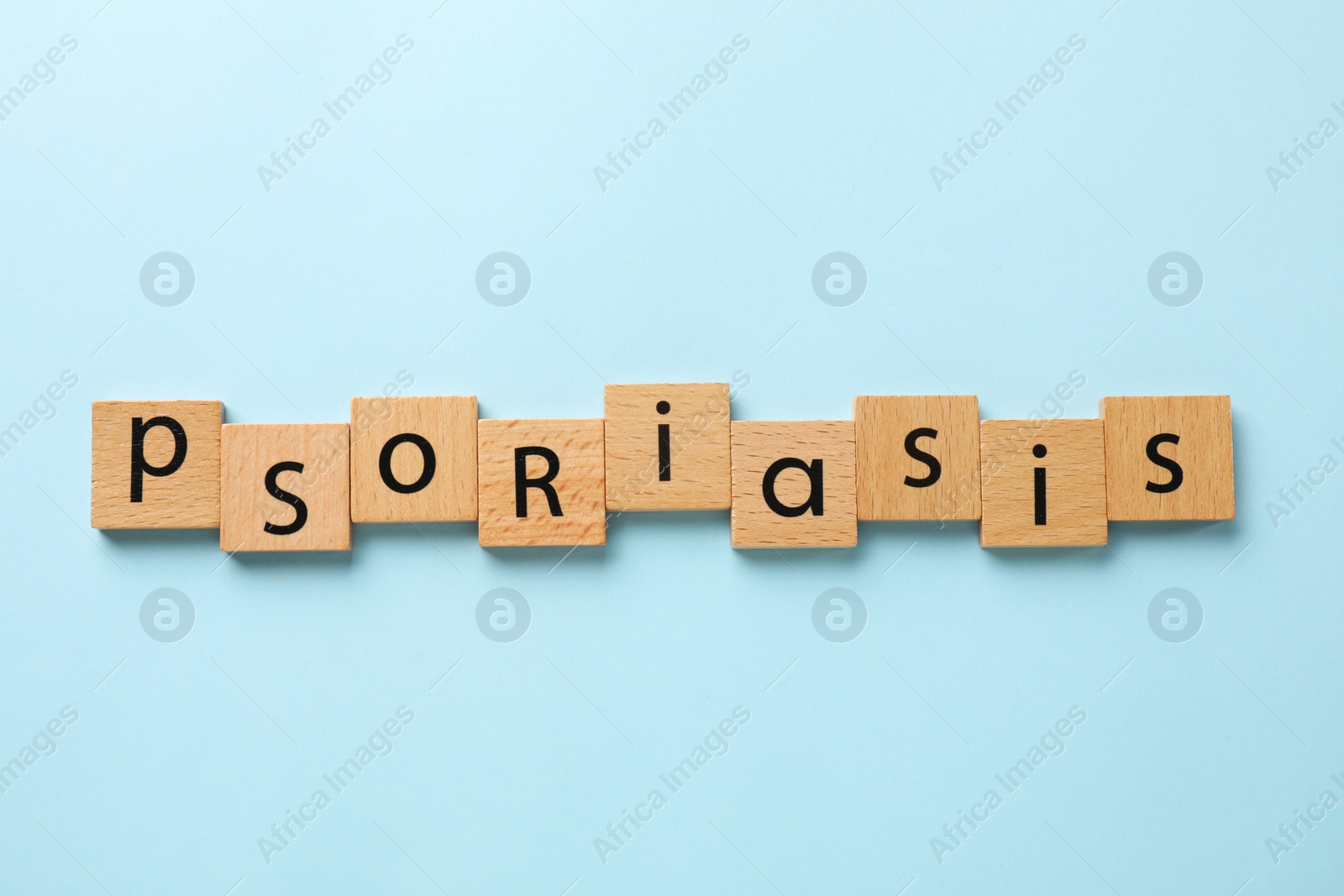 Photo of Word Psoriasis made of wooden squares with letters on light blue background, top view