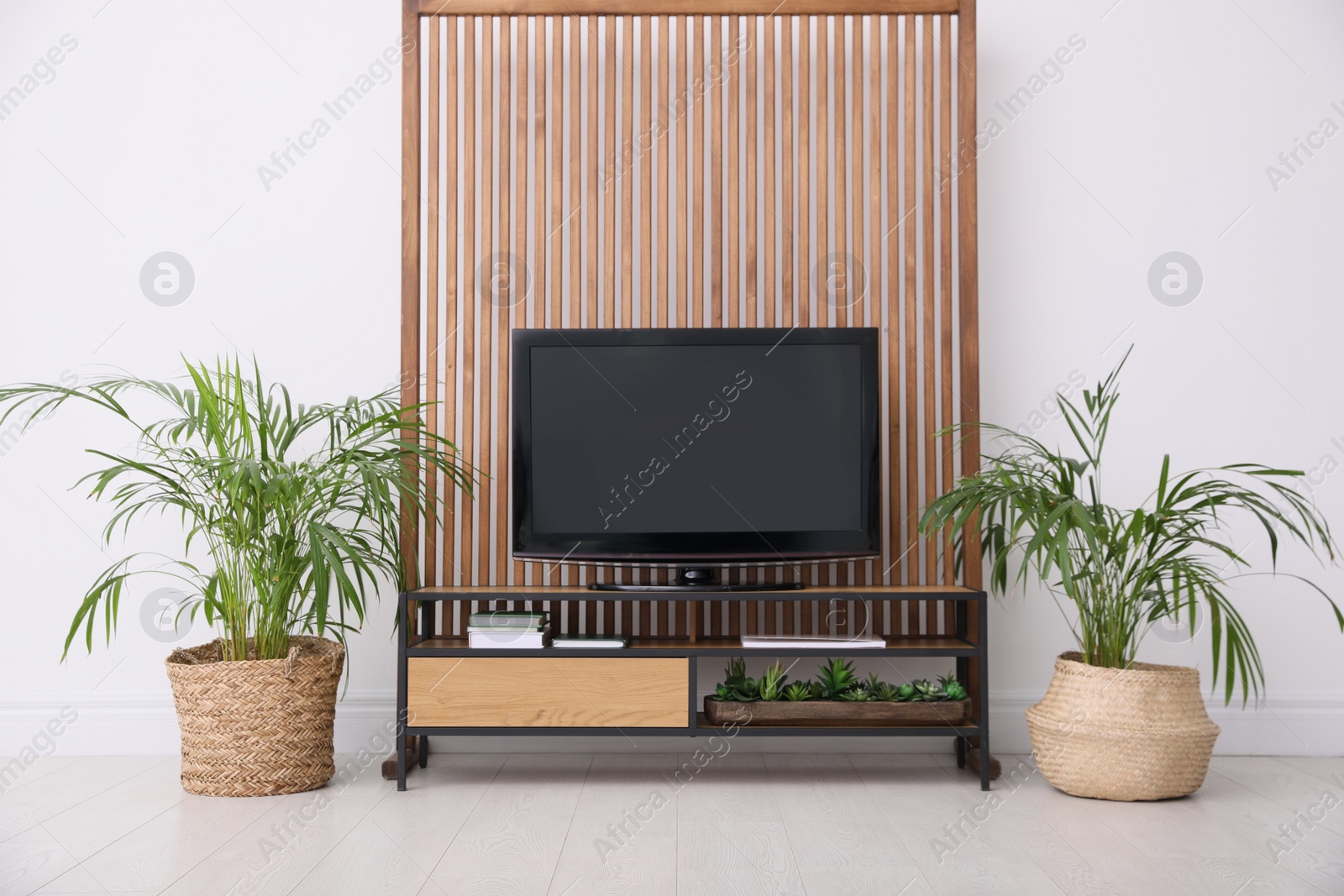 Photo of Elegant room interior with modern TV on cabinet and beautiful houseplants