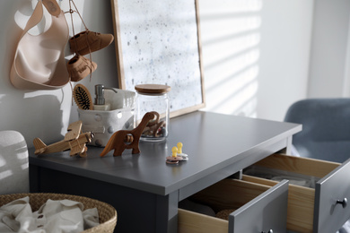 Wooden toys and different accessories on grey chest of drawers in child room