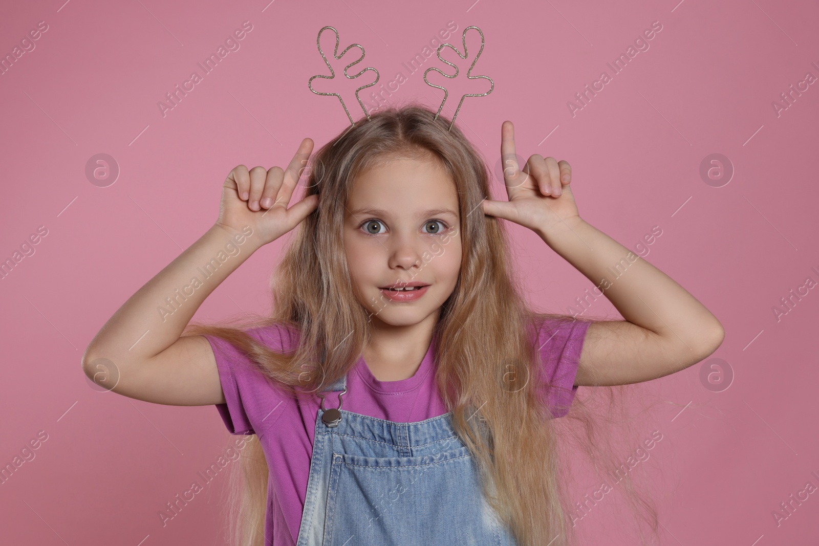 Photo of Playful girl wearing beautiful headband on pink background