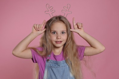 Playful girl wearing beautiful headband on pink background