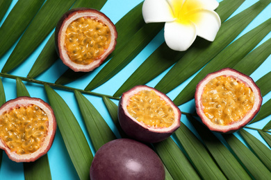 Photo of Passion fruits (maracuyas), flower and palm leaf on light blue background, flat lay
