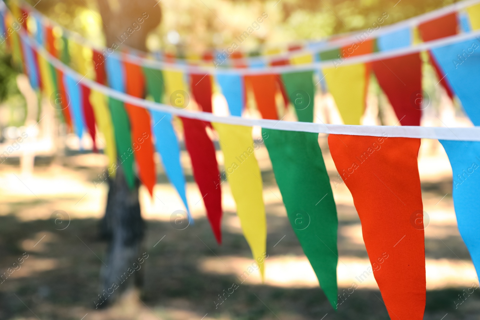 Photo of Colorful bunting flags in park. Party decor