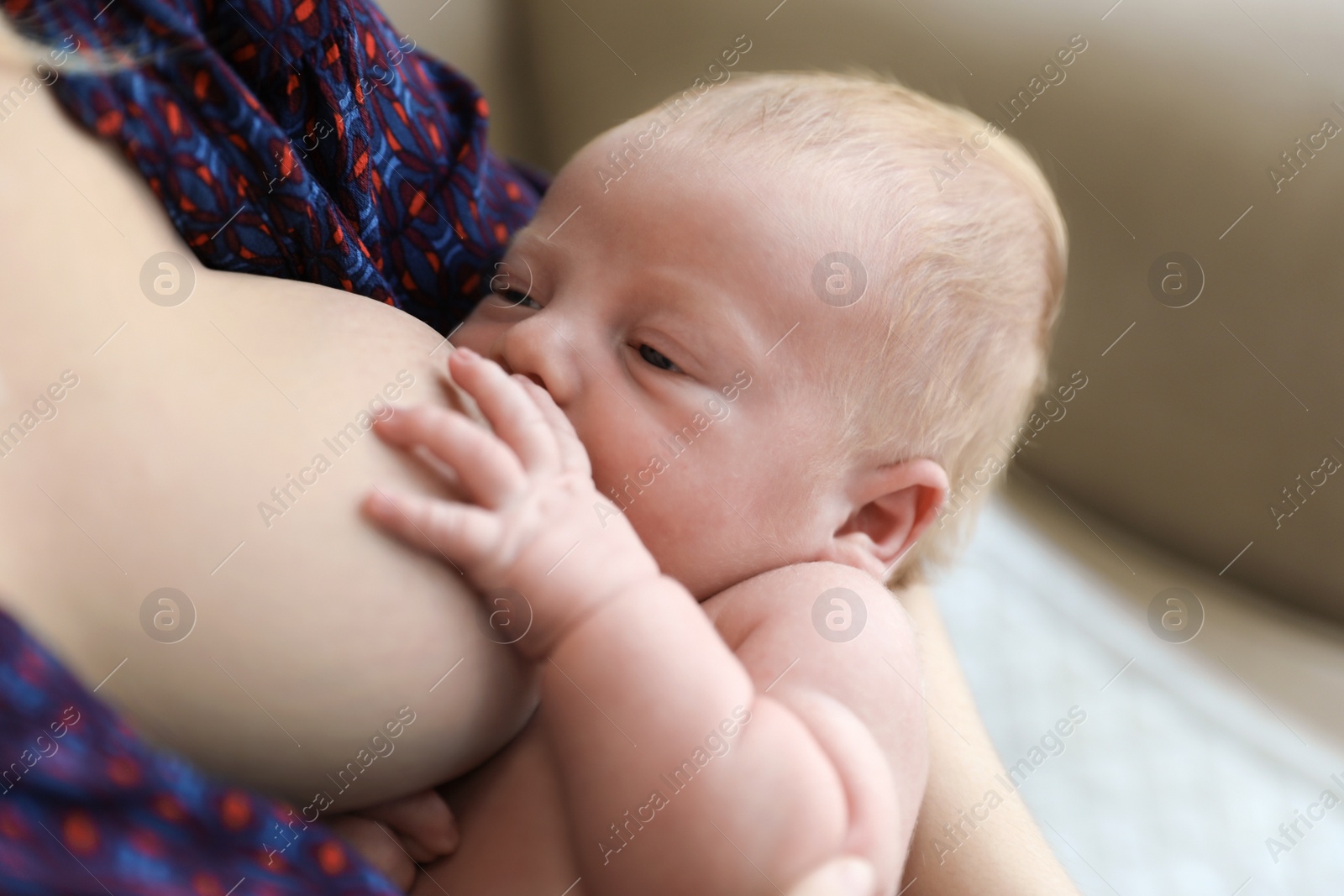 Photo of Woman breast feeding her little baby at home, closeup