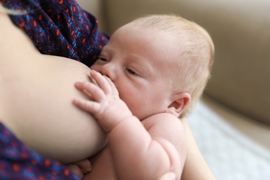 Photo of Woman breast feeding her little baby at home, closeup