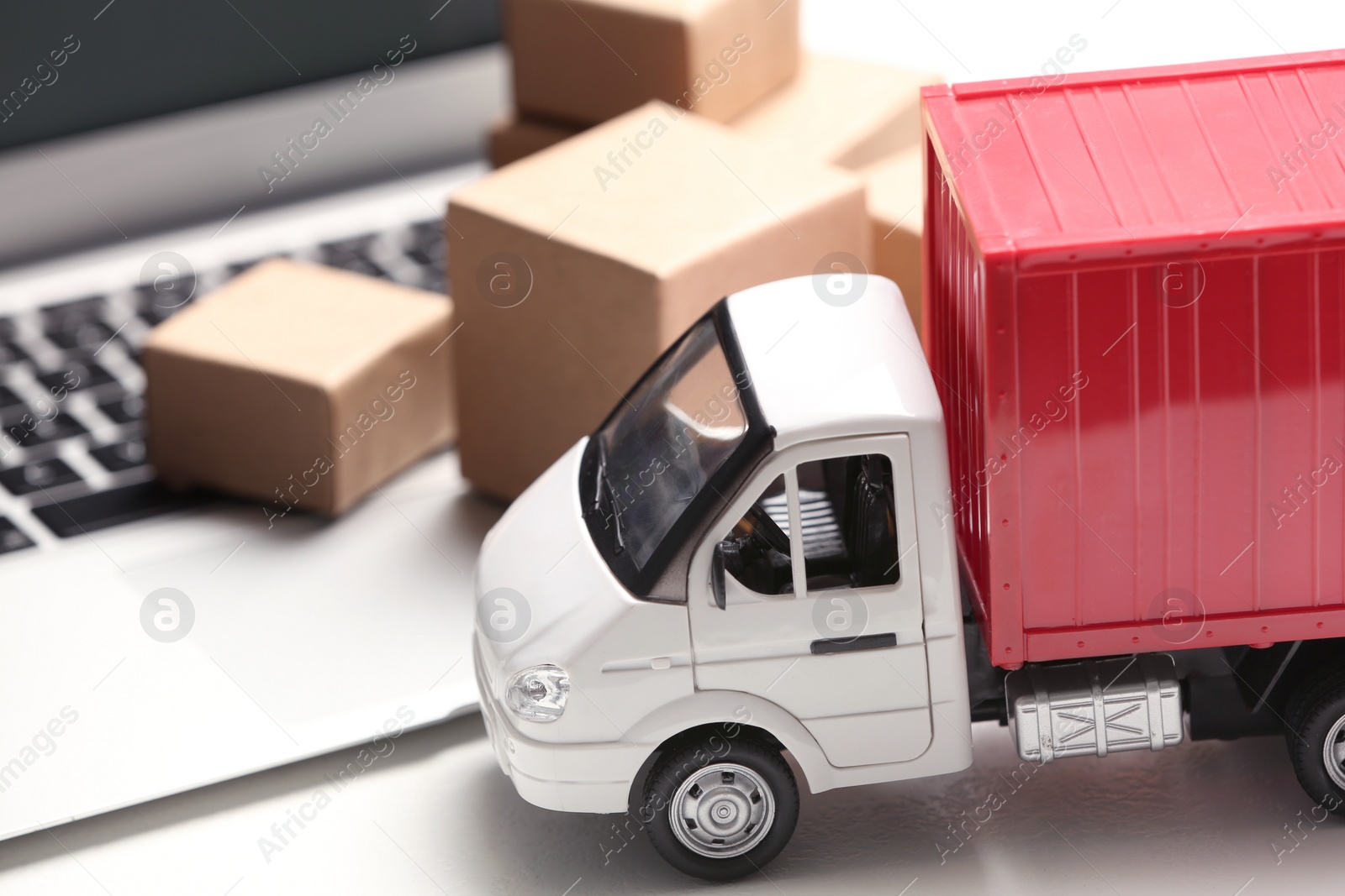 Photo of Toy truck near laptop on table. Logistics and wholesale concept