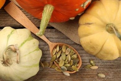 Photo of Spoon with peeled seeds and fresh pumpkins on wooden table, flat lay