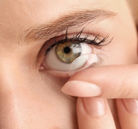 Young woman putting contact lens in her eye, closeup