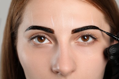 Photo of Beautician applying tint during eyebrows correction procedure, closeup