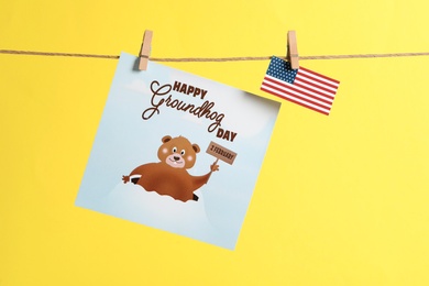 Photo of Happy Groundhog Day greeting card and American flag hanging on yellow background