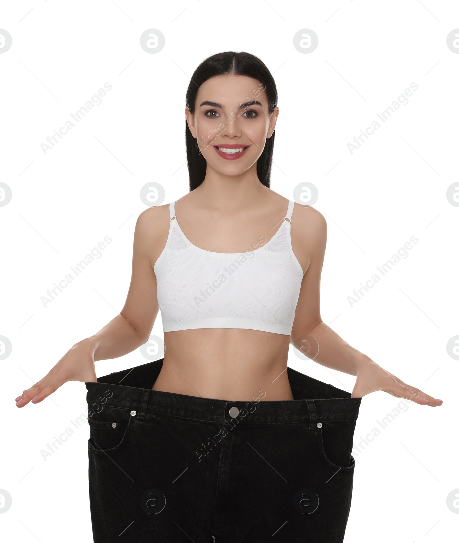 Photo of Young woman wearing big jeans after weight loss on white background