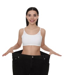 Young woman wearing big jeans after weight loss on white background