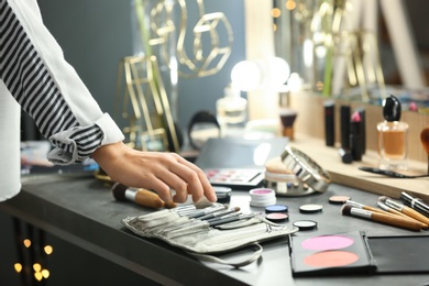 Photo of Professional makeup artist near dressing table with decorative cosmetics in beauty salon