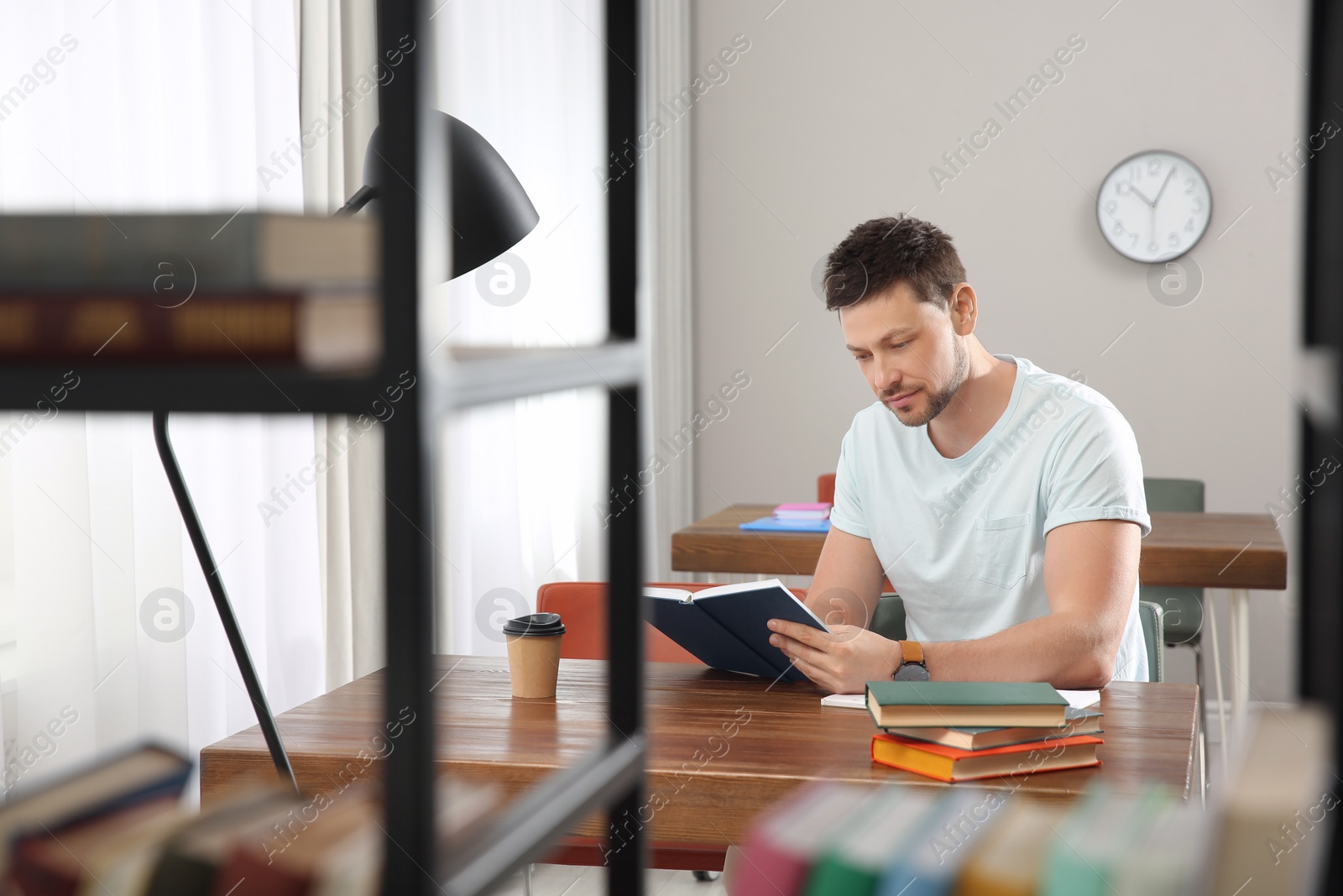 Photo of Man reading book at table in library