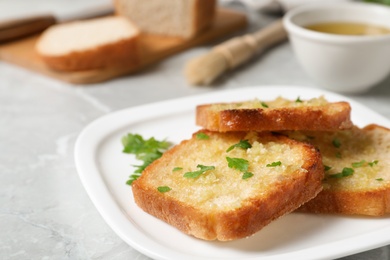 Photo of Slices of toasted bread with garlic and herb on light grey marble table, closeup