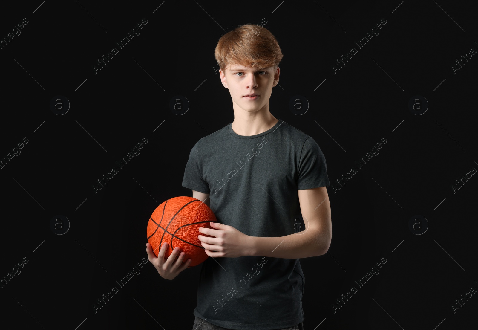 Photo of Teenage boy with basketball ball on black background