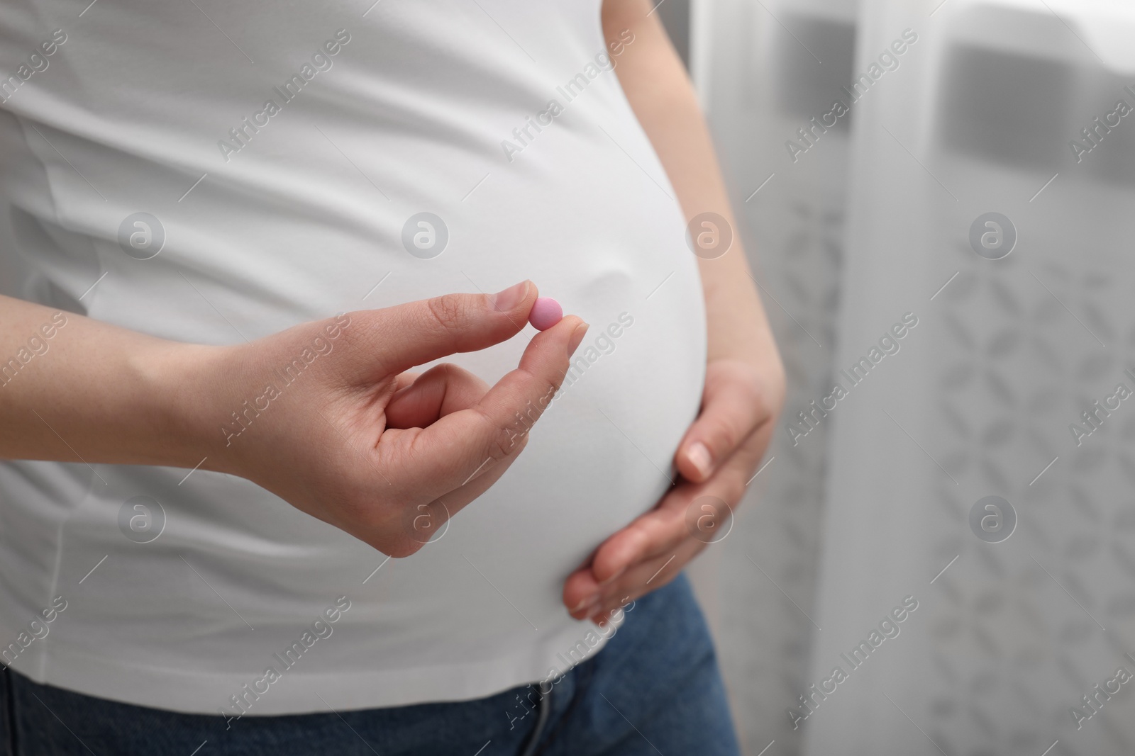 Photo of Pregnant woman with pill at home, closeup