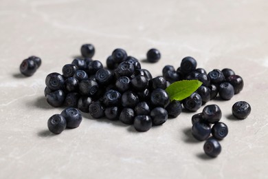 Ripe bilberries and leaf on light table, closeup